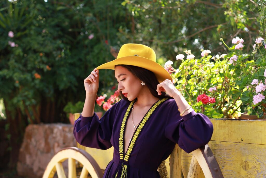 pexels-yesenia-mora-432270070-33388180 Woman sitting in the garden with a hat.